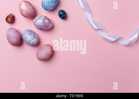 Bunte Eier, Wachteleier mit weißem Band auf rosa Hintergrund, Rahmen Raum. Gesunde Ernährung Konzept. Ansicht von oben, flach. Ostern Eier. Happy Osten Stockfoto