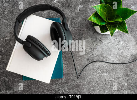 Das Hören von Hörbüchern Konzept mit Kopfhörer auf Stapel von Büchern auf Stein Hintergrund Stockfoto