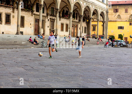 Jungs im Teenageralter kick ein socerball rund um die Piazza della Santissima Annunziata in Florenz, in der Region Toskana, Italien. Stockfoto