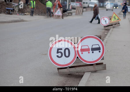 Verkehrszeichen, Umweg, Straße Reparatur auf der Straße Hintergrund, Lkw und Bagger gräbt Loch. Stockfoto