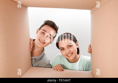 Fröhliche teen Paar auspacken, Karton und innen mit einem Lächeln auf dem Gesicht. Sie sind begeistert von der Schnelligkeit der Lieferung der Ware. Stockfoto