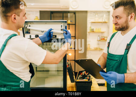 Techniker in Uniform Reparatur Kühlschrank zu Hause Stockfoto