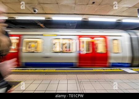 Ein Londoner U-Bahn, wie die Röhre bekannt, zieht in einem Bahnhof. Die bekannte Warnung "Mind the Gap" auf der Plattform Kante gemalt. Stockfoto