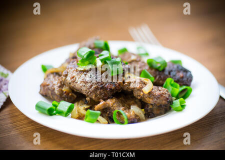 Gebratene Leber mit Zwiebeln in eine Platte auf einem hölzernen Stockfoto