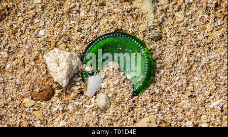 Sand, Steine und der Unterseite einer zerbrochenen Weinflasche Stockfoto