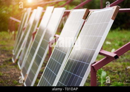 Zeile der neuen glänzenden Solar Photovoltaik Panele arrangiert im Freien auf sonnigen Sommertag, Metall künftige Plattform Rahmen bereit für die Installation lehnte. Erneuern Stockfoto