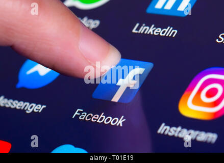 Finger, mit dem Facebook App auf einem Touchscreen auf einem Tablet-PC oder Handy Gerät. Laden von Facebook Anwendung. Facebook Verknüpfung. Stockfoto