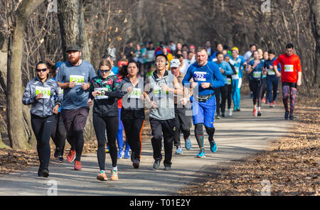 ALMATY, Kasachstan - 16. MÄRZ 2019: eine dichte Gruppe von unbekannten Männern und Frauen läuft durch ein Wäldchen im Frühjahr Marathon in der Stadt Almaty Stockfoto
