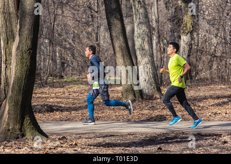 ALMATY, Kasachstan - 16. MÄRZ 2019: Ein unbekannter Mann läuft durch ein Wäldchen im Frühjahr Marathon in der Stadt Almaty, in einem Hain nach Namen Stockfoto