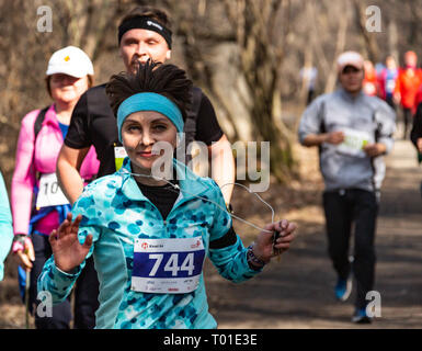 ALMATY, Kasachstan - 16. MÄRZ 2019: eine dichte Gruppe von unbekannten Männern und Frauen läuft durch ein Wäldchen im Frühjahr Marathon in der Stadt Almaty Stockfoto