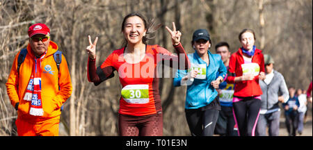 ALMATY, Kasachstan - 16. MÄRZ 2019: eine dichte Gruppe von unbekannten Männern und Frauen läuft durch ein Wäldchen im Frühjahr Marathon in der Stadt Almaty Stockfoto