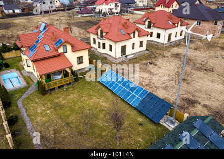 Antenne Blick von oben auf die Wohngegend mit neuen Häusern mit Dach Solar Photovoltaik Panele, wind turbine Mühle und Stand-alone-Fassade solar panel Syste Stockfoto