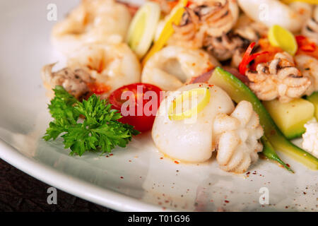 Baby Tintenfisch und Gemüse auf einem weißen Teller Stockfoto