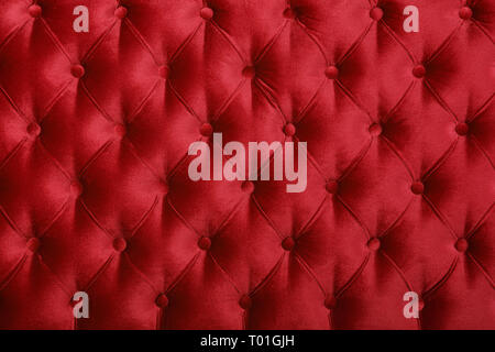 Maroon red velvet capitone Background, retro Chesterfield Stil kariert Soft getuftete Stoffmöbel Rautenmuster Dekoration mit Tasten Stockfoto