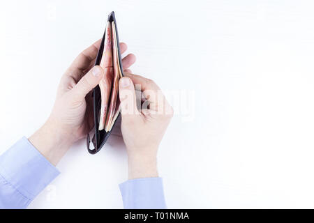 Den Beutel mit dem Geld in der Hand auf einem weißen Hintergrund Stockfoto