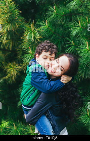 Mutter und Sohn umarmen, Spielen im Park im Frühling sonniger Tag, glückliches Familienleben Stockfoto