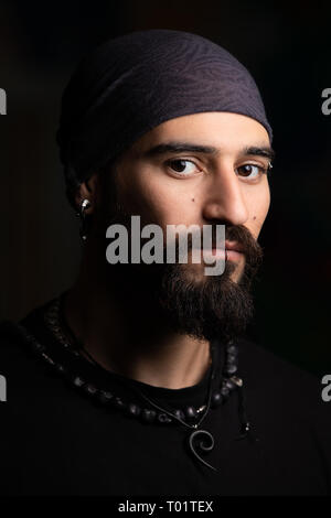 Dunkel, Nahaufnahme, Porträt eines Mannes mit Piercings und bandana. Stockfoto