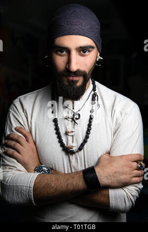 Dunkel, Nahaufnahme, Porträt eines Mannes mit Piercings und bandana. Stockfoto