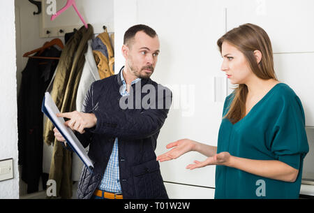 Portrait von genervt Schuldeneintreiber und schockiert junge Frau mit überfälligen Zahlung zu Hause Tür Stockfoto