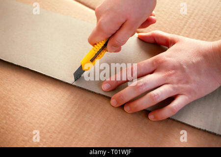 Papier Messer in Person Hände Schneiden von Pappe. Close-up. Stockfoto