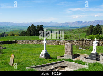 Blick über den alten Friedhof mit Grabsteinen zu ausgedehnten ländlichen Gebieten und die fernen Hügel in Central Otago Neuseeland Stockfoto