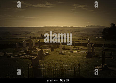 Vintage Style Bild Blick über den alten Friedhof mit Grabsteinen zu ausgedehnten ländlichen Gebieten und die fernen Hügel in Central Otago Neuseeland Stockfoto