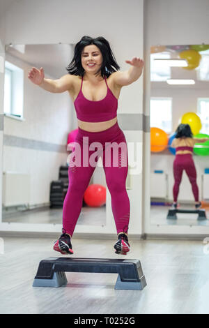 Sportliche Mädchen springen auf Stepper in der Turnhalle. Übung Muskel. Das Konzept der Sport, eine gesunde Lebensweise, Gewicht zu verlieren. Stockfoto