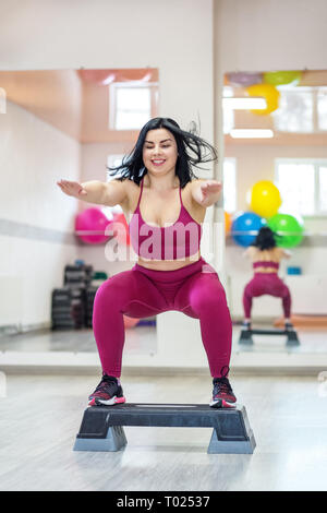 Athletische Frau springen auf Stepper in der Turnhalle. Übung Muskel. Das Konzept der Sport, eine gesunde Lebensweise, Gewicht zu verlieren. Stockfoto