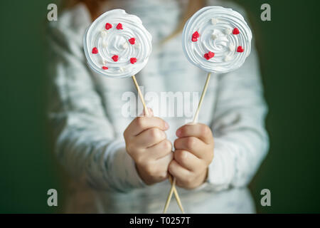 Köstliche meringue Süßigkeiten mit Herzen in Kinderhand. Das Konzept von Süßigkeiten, Party, Bäckerei. Stockfoto