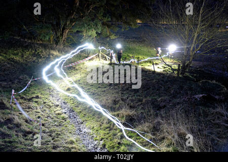 INNERLEITHEN, Traquair House & Immobilien, UK. 16.Mär.2019. 13 mächtigen Deerstalker Adventure Race Bildunterschrift: Läufer Ansatz das Wasser, leichte Spuren von Kopf Fackeln in dieser langen Belichtungszeit Bild. Die 13 mächtigen Deerstalker, Rat Race, Abenteuersport. Die Ausgefallensten, nachts, Trail Running Event im BRITISCHEN Kalender 3000 hardy Trailrunner wird in Richtung Traquair House, Innerleithen, in den schottischen Borders, für die Mächtigen Deerstalker, der größten und härtesten 'des o in themed Tweed "Nacht ausführen, um in Großbritannien inszeniert werden. (Foto: Rob Grau) Stockfoto