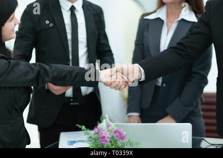 Zwei Geschäftsfrauen Händeschütteln über einen Schreibtisch, wenn Sie einen Deal schließen Stockfoto