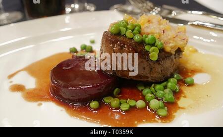 Medium Steak serviert mit Yam gekrönt mit grünen Erbsen und Gewürze Stockfoto