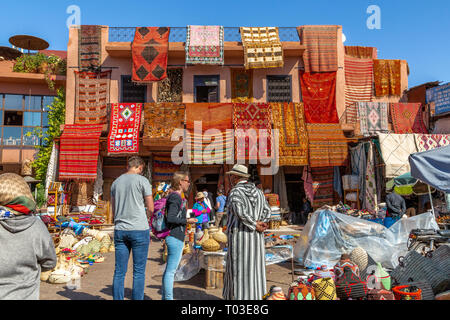 Farbenfrohe marokkanische Teppiche vor dem Souk-Shop in Marrakesch, Straßenszene auf dem Medina-Markt mit traditionellen Textilien und Einkaufsmöglichkeiten. Stockfoto