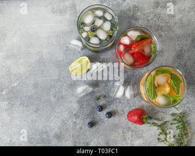 Verschiedene Zitrusfrüchte Wasser, Limonaden oder Mojitos infundiert, mit Kalk und Blaubeeren, Orangen und Erdbeeren und Basilikum in Gläsern, Diät Entgiftung Getränke, Gr Stockfoto
