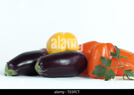 Paprika, Auberginen und Zweige Petersilie auf einem weißen Hintergrund. Stockfoto