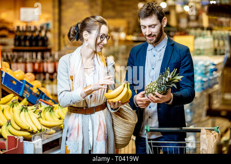 Junge und glückliche Paar Kauf von Lebensmitteln, frischem Obst im Supermarkt Stockfoto