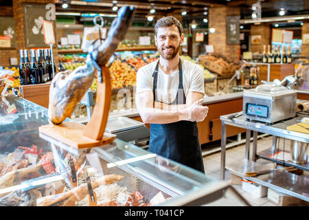 Porträt einer stattlichen Verkäufer stehen an der Theke mit jamon im Supermarkt Stockfoto