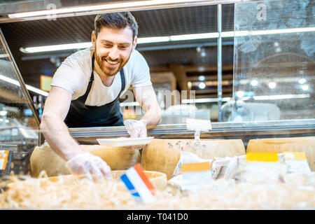 Porträt einer Geschäft Arbeiter packen Parmesan in die Spur, den Verkauf von Käse im Supermarkt Stockfoto