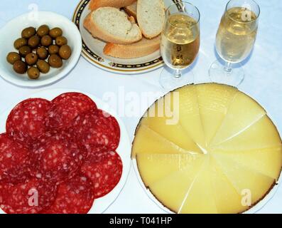 Eine Auswahl an spanischen Tapas wie Manchego Käse, grünen Oliven und Salami mit zwei Gläser fino Sherry, Andalusien, Spanien. Stockfoto