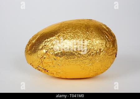 Osterei verpackt in Goldfolie vor einem weißen Hintergrund, UK. Stockfoto