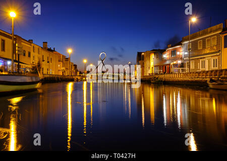 Kanal in Aveiro mit kreisförmigen Fußgängerbrücke Hintergrund während der blauen Stunde. Lange Belichtung. In Aveiro, Portugal, Stockfoto