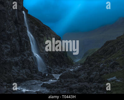 Lightbeam auf den Wasserfall in kleinen Tal bei Einbruch der Nacht, Färöer Inseln. Stockfoto