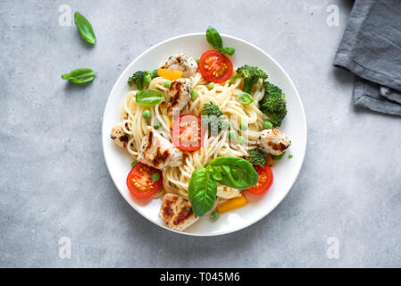 Huhn und Gemüse Pasta. Spaghetti Pasta mit gegrilltem Hähnchen Fleisch, Gemüse und Basilikum, Ansicht von oben, kopieren. Saisonale Pasta Primavera Rezept. Stockfoto