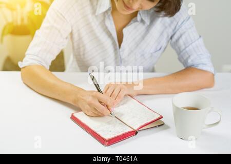 Frau mit einem Notebook an einem Tisch sitzen mit einer Tasse Tee Stockfoto