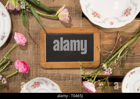 Alte Schiefertafel Schiefertafel, auf rustikale Holzplanken Hintergrund mit romantischen Porzellan und Blumen. Für Cafés, Menü Konzept, Banner, sicher das Datum, die Hochzeit. Stockfoto