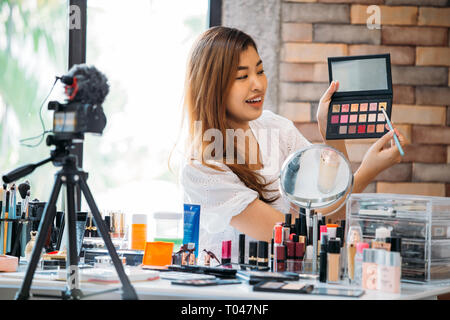 Hübsche asiatische Frau Aufnahme Makeup Tutorial Video über Kosmetika mit Handy auf den Dreifuß . Stockfoto