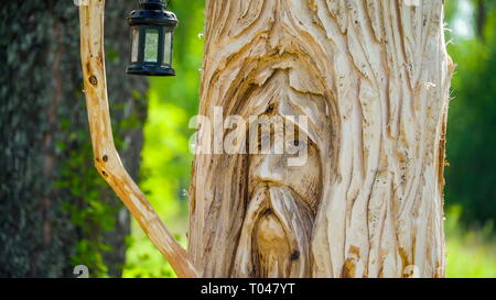 Ein Bild, das auf den Stamm eines Holz- Baum eine schöne Statue für Dekorationen mit einem hängenden Lampe auf der Seite geschnitzt Stockfoto