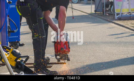 Ein Arbeiter in der Baustelle Schneiden einer eisernen Stange mit einem elektronischen Cutter mit Funken aus Stockfoto