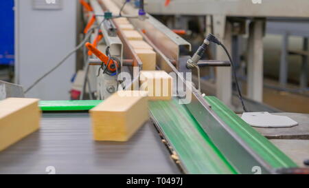 Blick von der kleinen hölzernen Blöcke, die von der Maschine innerhalb des Sägewerks Stockfoto