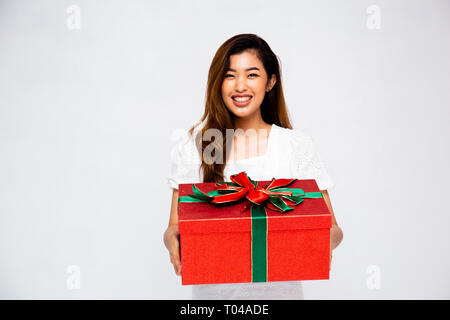 Schönen asiatischen Frauen lächeln und Große Geschenkbox Kamera beim Stehen auf grauem Hintergrund Stockfoto